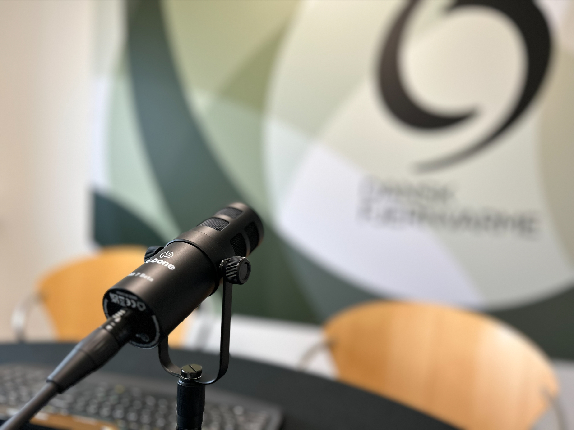 genrebillede af webinar med en mikrofon i fokus og dansk fjernvarmes logo i baggrunden